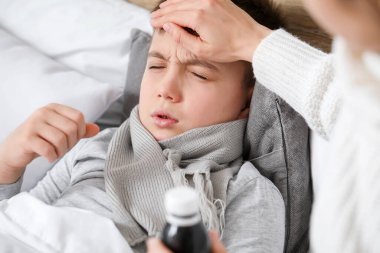 Anne, oğluna evde hasta bir şekilde bakıyor.