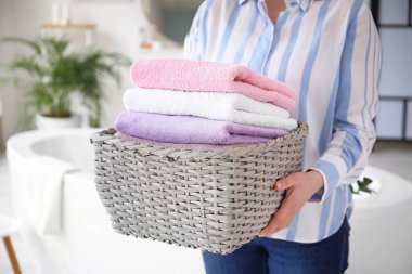 Evde çamaşır sepeti olan bir kadın var.