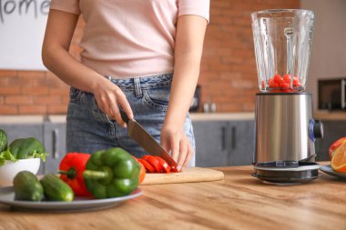 Genç bir kadın mutfakta smoothie yapıyor.
