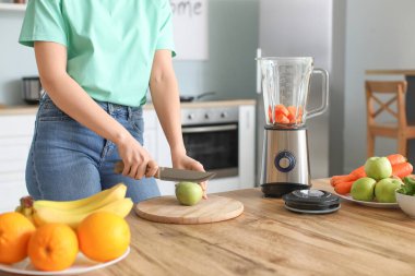 Genç bir kadın mutfakta smoothie yapıyor.