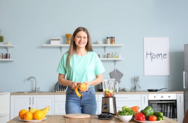 Genç bir kadın mutfakta smoothie yapıyor.