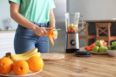 Genç bir kadın mutfakta smoothie yapıyor.