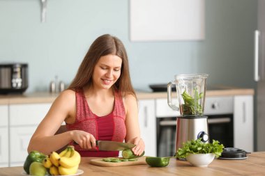 Sportif kadın evde mutfakta smoothie yapıyor.