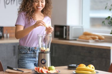 Genç bir kadın mutfakta smoothie yapıyor.