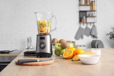 Modern blender, taze meyve ve mutfak masasında kesim tahtası.