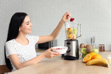 Genç bir kadın mutfakta meyve püresi yapıyor.