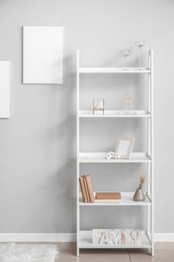 Gri duvarın yanında şık dekorlu raflar.