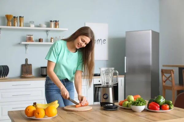 Young woman making smoothie in kitchen at home