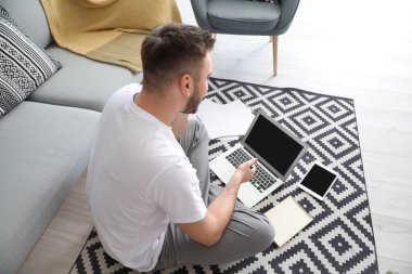 Bilgisayarlı genç adam evde çalışıyor.