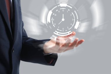 Gri arka planda sanal saati olan bir iş adamı. Zaman yönetimi kavramı