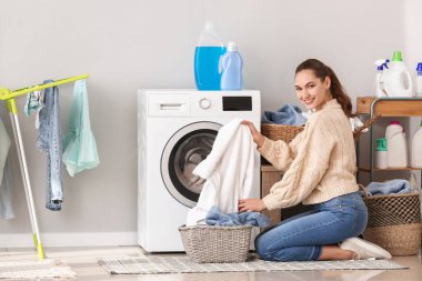 Evde çamaşır yıkayan genç bir kadın.