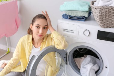 Genç bir kadın banyoda çamaşır yıkıyor.