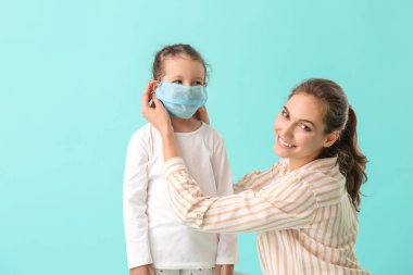 Anne kızının yüzüne koruyucu bir maske takıyor.