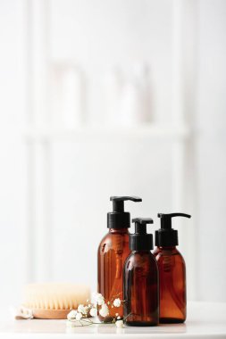 Banyoda farklı duş jelleri, fırça ve çiçekler var.