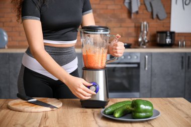 Sportif kadın evde mutfakta smoothie yapıyor.