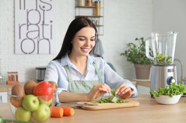 Evde mutfakta sebze püresi yapan genç bir kadın.