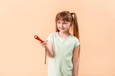 Arka planda el feneri olan küçük bir kız.