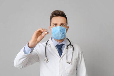 Gri arka planda el feneri olan erkek doktor.