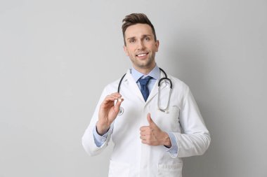 Gri arka planda el feneri olan erkek doktor.