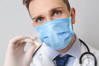 Gri arka planda el feneri olan erkek doktor.