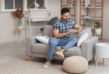 Evde tablet bilgisayarı olan genç bir adam.