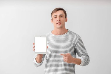 Arka planda tablet bilgisayarı olan genç bir adam.