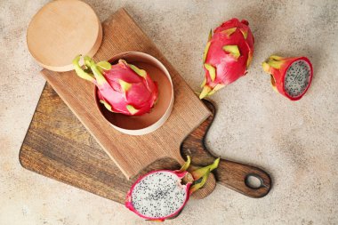 Gri arka planda lezzetli ejderha meyveleri olan tahtalar.