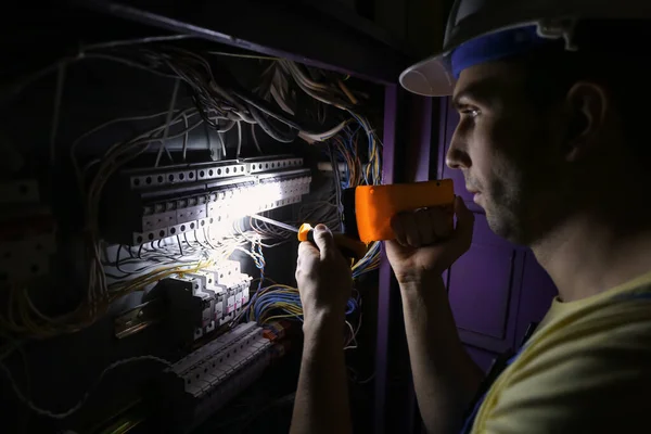 Male Electrician Flashlight Repairing Distribution Board — Stock Photo, Image