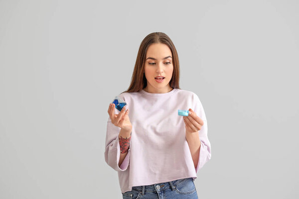 Young woman with detergents on grey background