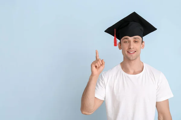 Mladý Muž Maturitní Čepici Zvednutým Ukazováčkem Světlém Pozadí — Stock fotografie