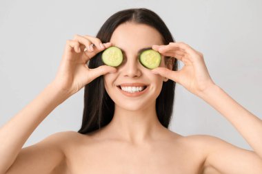 Salatalık dilimleri ve açık arkaplanda güzel genç bir kadın.