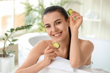 Banyoda salatalık dilimleri olan güzel genç bir kadın.