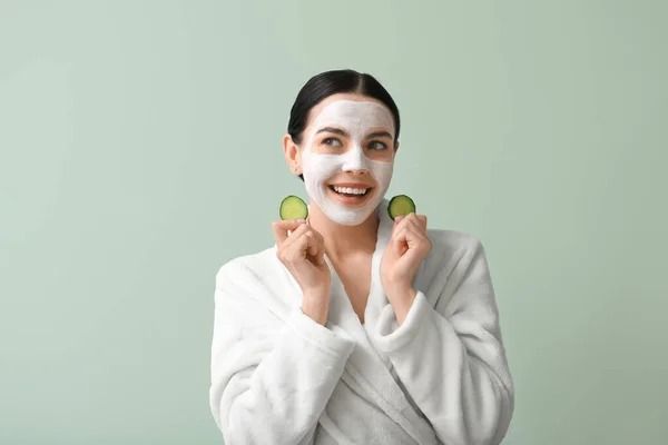 Schöne Junge Frau Mit Gurkenscheiben Und Gesichtsmaske Auf Farbigem Hintergrund — Stockfoto