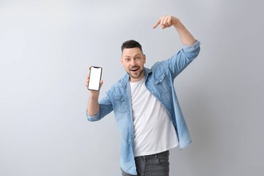 Gri arka planda cep telefonu olan yakışıklı bir adam.