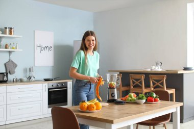 Genç bir kadın mutfakta smoothie yapıyor.