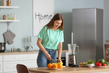 Genç bir kadın mutfakta smoothie yapıyor.