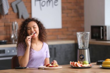 Genç bir kadın mutfakta smoothie yapıyor.