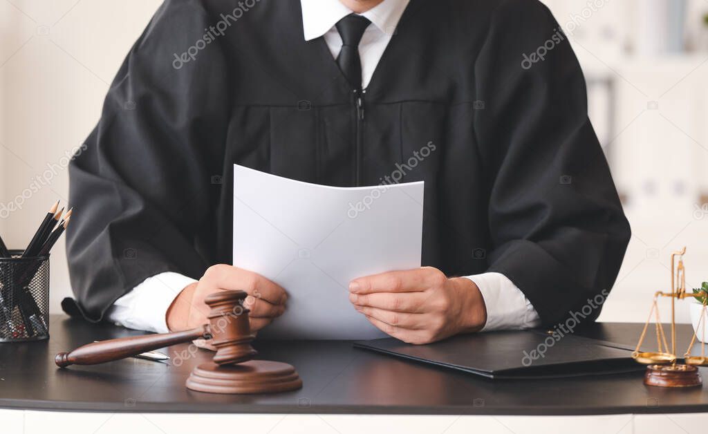 Male judge with documents at table in office