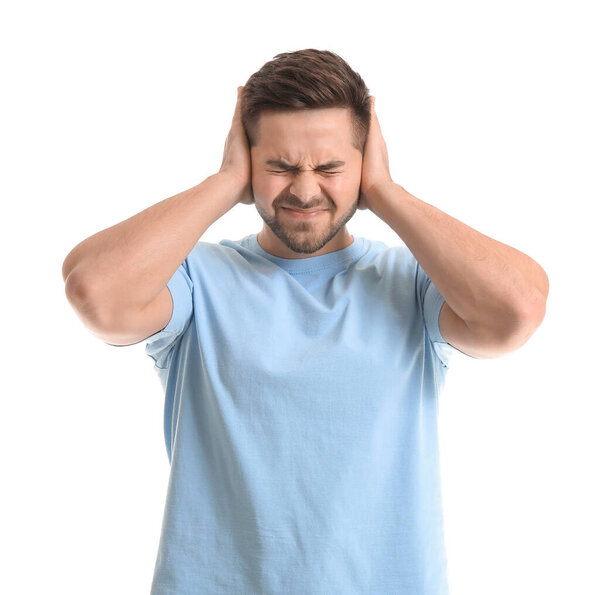 Young man suffering from loud noise on white background