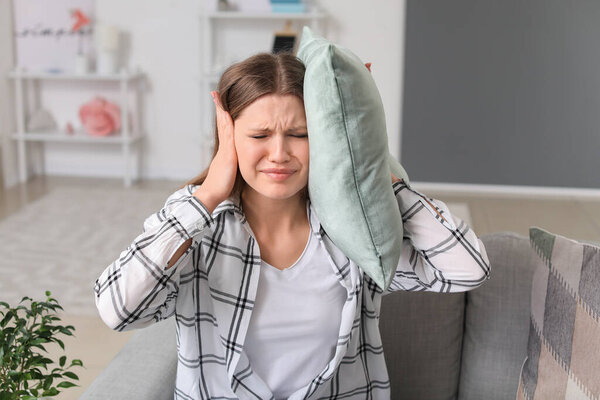 Молодая женщина страдает от громкого шума дома
