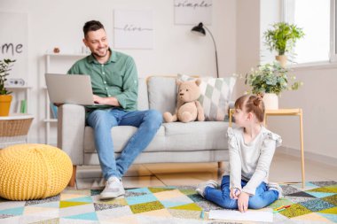 Evde kızıyla birlikte çalışan bir baba.