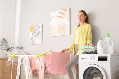 Genç bir kadın banyoda çamaşır yıkıyor.