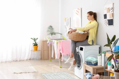 Genç bir kadın banyoda çamaşır yıkıyor.