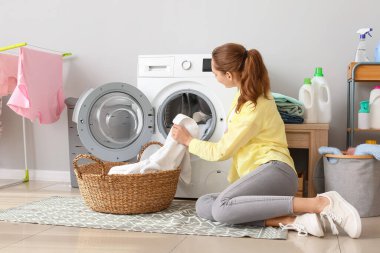 Genç bir kadın banyoda çamaşır yıkıyor.