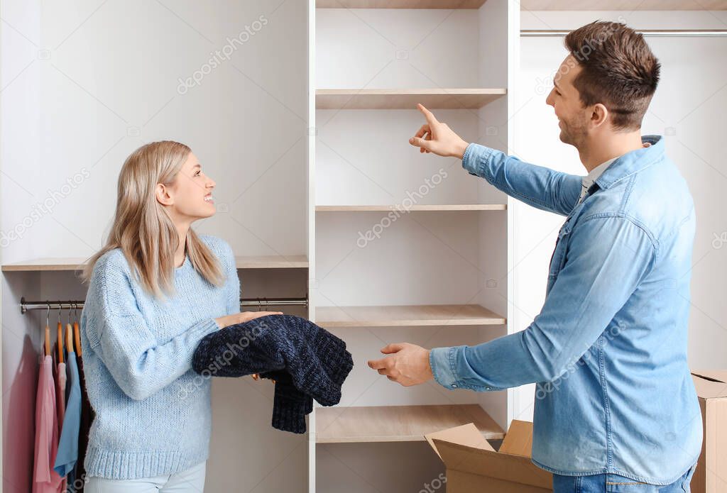 Young couple unpacking clothes in their new flat on moving day