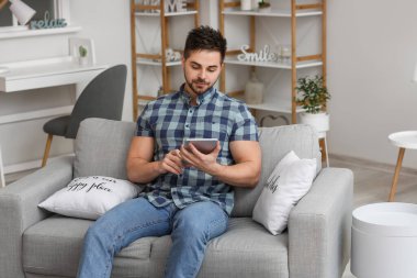 Evde tablet bilgisayarı olan genç bir adam.