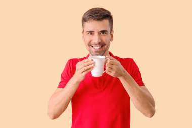 Arka planda bir fincan sıcak kahvesi olan genç adam.