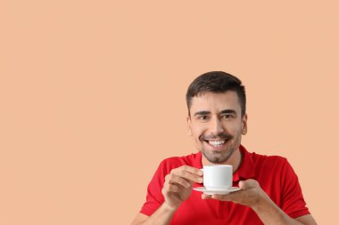 Arka planda bir fincan sıcak kahvesi olan genç adam.