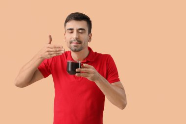 Arka planda bir fincan sıcak kahvesi olan genç adam.