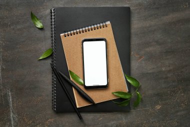 Koyu arkaplanda cep telefonu ve kırtasiye